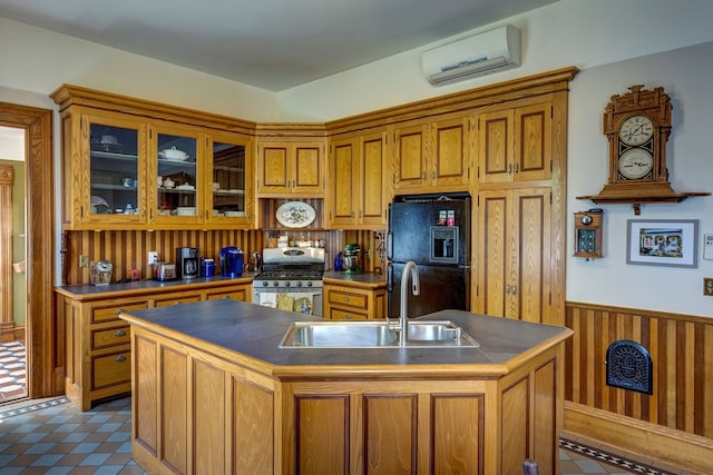 kitchen featuring a kitchen island with sink, light tile flooring, a wall unit AC, black fridge with ice dispenser, and gas range