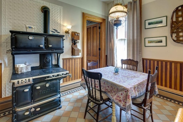 73 Elm St, Otsego, NY 13326 - tiled dining room with a wood stove, a wainscoted wall, an inviting chandelier, and baseboard heating