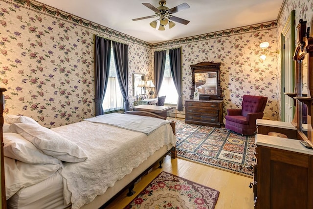 bedroom with baseboard heating, ceiling fan, and hardwood / wood-style floors