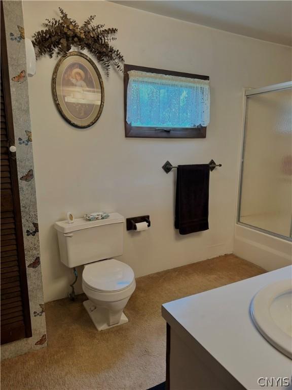 bathroom featuring vanity, toilet, and a shower with door