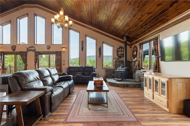 living room with a wood stove, an inviting chandelier, crown molding, wood-type flooring, and lofted ceiling