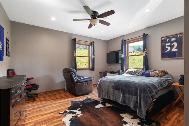 bedroom with multiple windows, hardwood / wood-style flooring, and ceiling fan