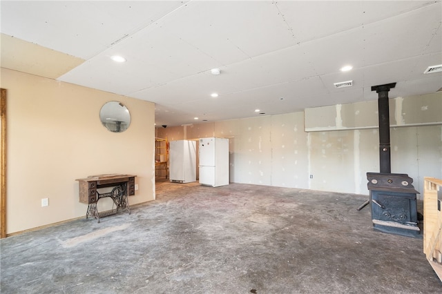 unfurnished living room with a wood stove and concrete flooring