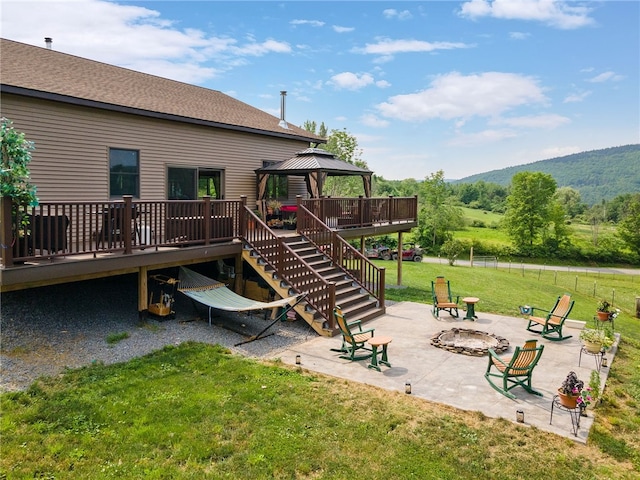 exterior space featuring a gazebo, a fire pit, a patio area, a deck with mountain view, and a yard