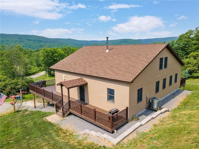 rear view of property with a lawn, a deck, and central AC