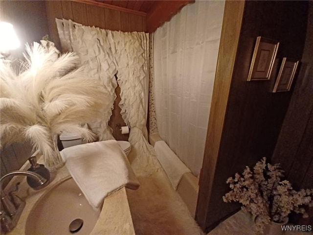 bathroom with toilet, shower / bath combo with shower curtain, and a sink