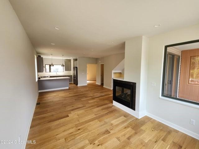 unfurnished living room with a multi sided fireplace and light hardwood / wood-style floors