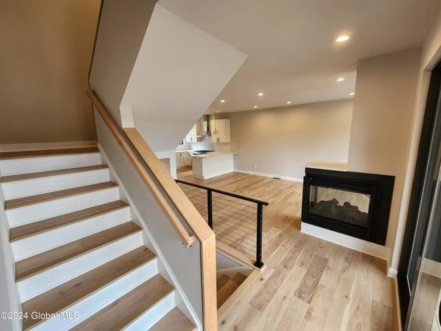 stairway with a multi sided fireplace and hardwood / wood-style flooring