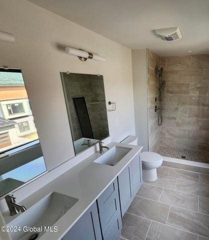 bathroom with tiled shower, vanity, and toilet