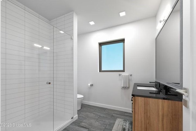 bathroom featuring vanity, toilet, and a tile shower