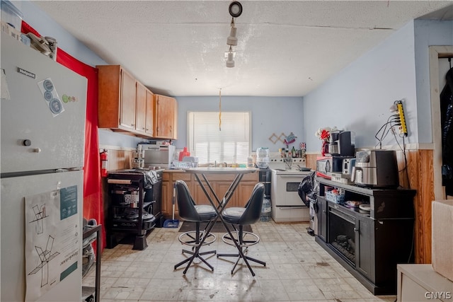 kitchen with white appliances, a textured ceiling, light tile floors, and pendant lighting