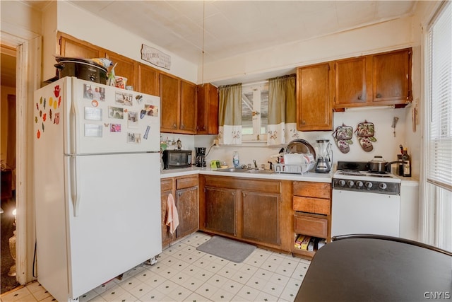 kitchen featuring white appliances, sink, and light tile flooring