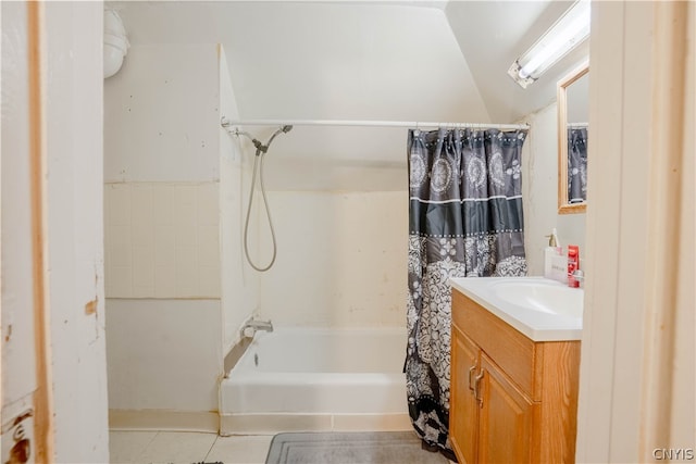 bathroom with vaulted ceiling, tile flooring, vanity, and shower / tub combo