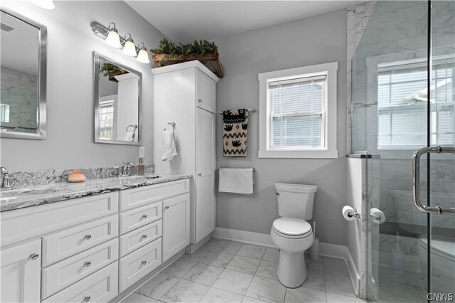 bathroom with toilet, vanity, and a shower with shower door