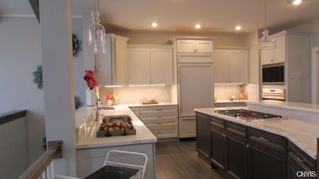 kitchen with hanging light fixtures, stainless steel gas cooktop, dark hardwood / wood-style floors, sink, and white cabinetry