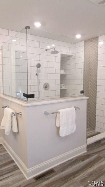 bathroom with wood-type flooring and tiled shower