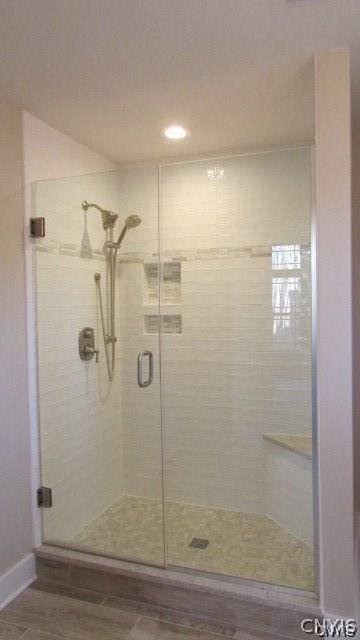 bathroom with a shower with door and hardwood / wood-style floors