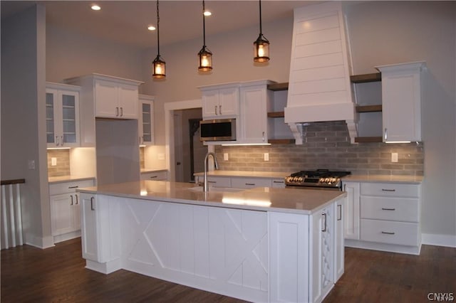 kitchen featuring a kitchen island with sink, stove, pendant lighting, and white cabinetry