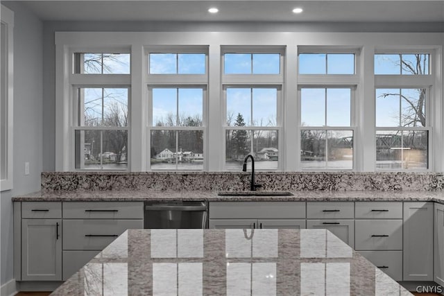 kitchen featuring sink, white cabinets, dishwasher, light stone counters, and a healthy amount of sunlight