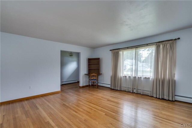 spare room with a baseboard radiator and light hardwood / wood-style flooring