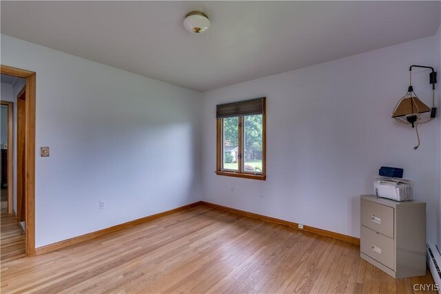 empty room with light hardwood / wood-style floors and baseboard heating