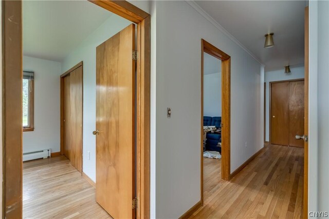 corridor with light hardwood / wood-style floors, crown molding, and a baseboard radiator