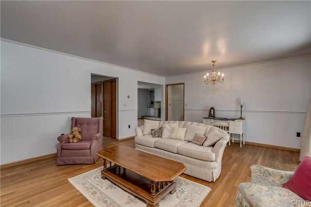 living room featuring ornamental molding, light hardwood / wood-style flooring, and an inviting chandelier