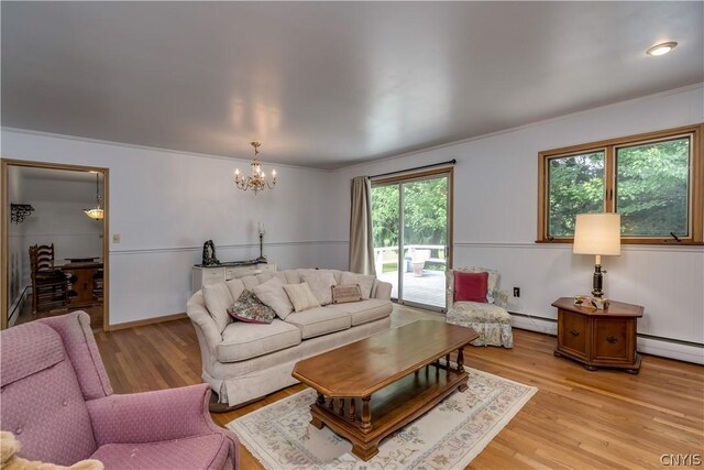 living room with a chandelier, light hardwood / wood-style floors, a baseboard radiator, and ornamental molding