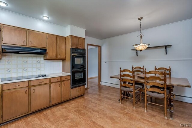 kitchen featuring tasteful backsplash, a baseboard heating unit, black appliances, pendant lighting, and light hardwood / wood-style flooring