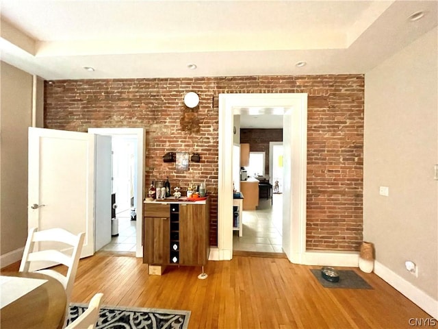 interior space with brick wall and light hardwood / wood-style flooring