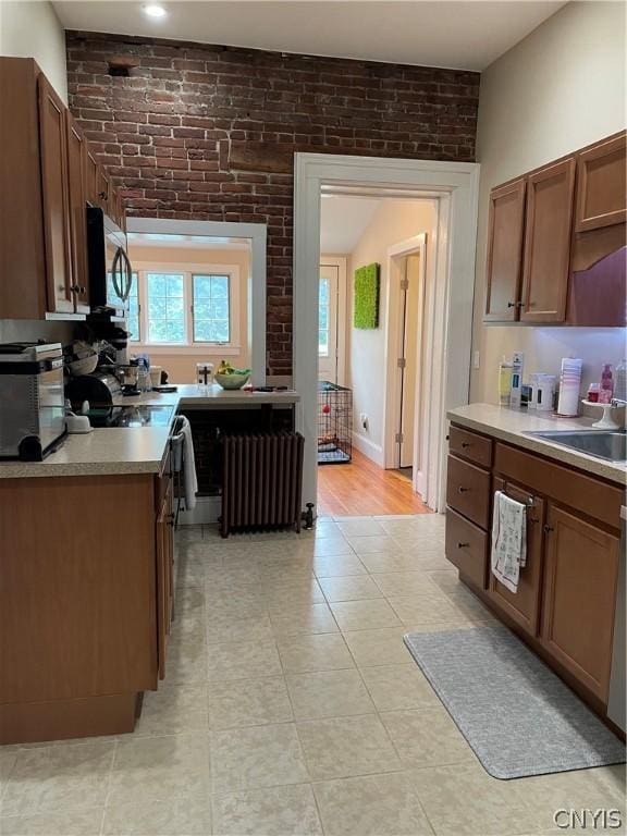 kitchen with sink, brick wall, and radiator heating unit