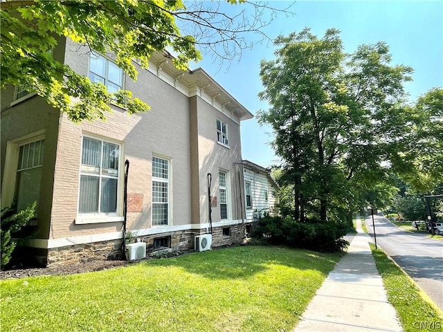 view of side of home with ac unit and a yard