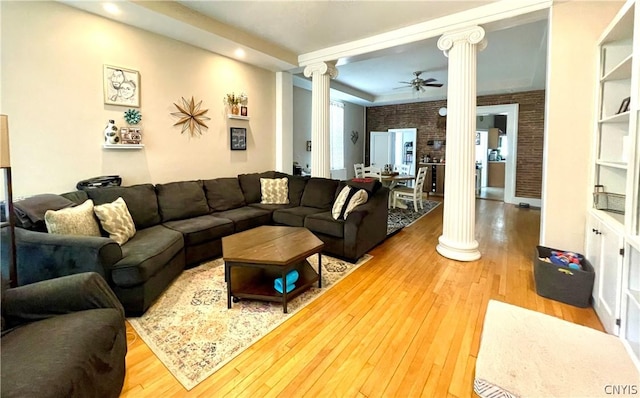 living room with ceiling fan, brick wall, ornate columns, and hardwood / wood-style floors