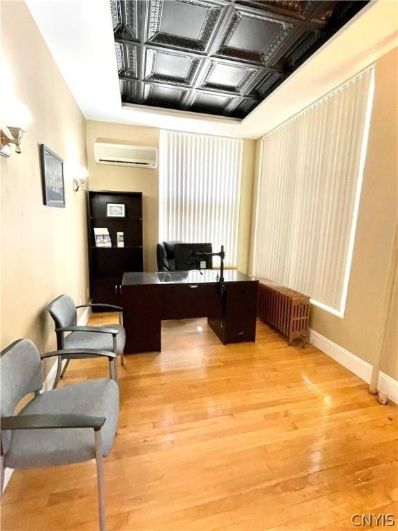 home office with hardwood / wood-style floors, radiator heating unit, and a wall mounted AC