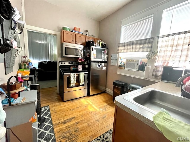 kitchen with sink, stainless steel appliances, a healthy amount of sunlight, and light hardwood / wood-style flooring