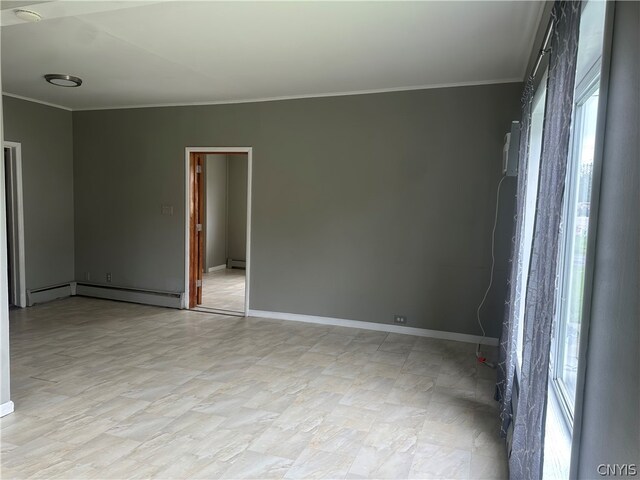 empty room featuring plenty of natural light, a baseboard radiator, and ornamental molding