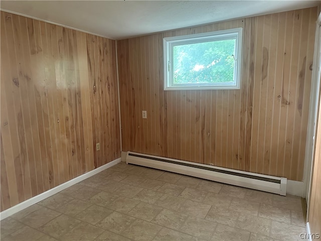 tiled spare room featuring baseboard heating and wooden walls