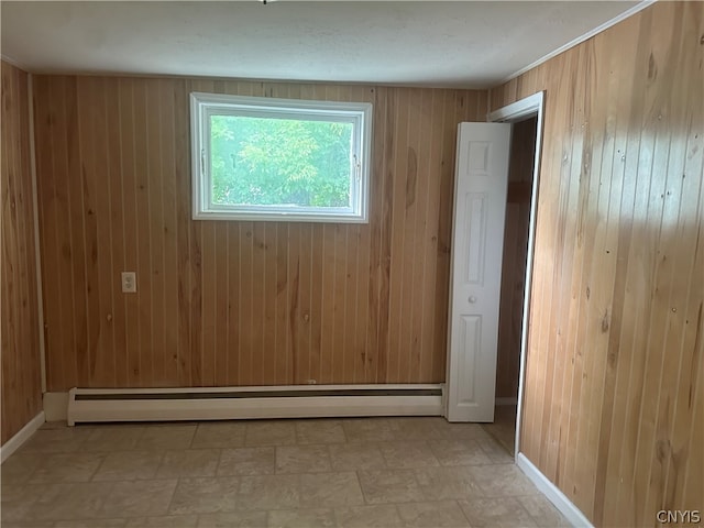 unfurnished room with baseboard heating, wooden walls, and light tile flooring