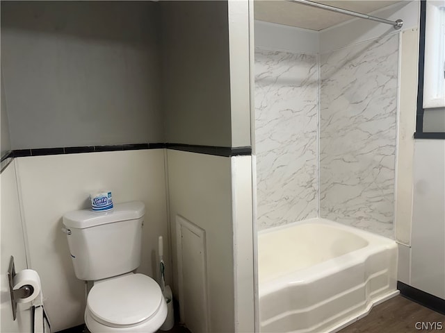 bathroom with hardwood / wood-style flooring, tiled shower / bath combo, and toilet