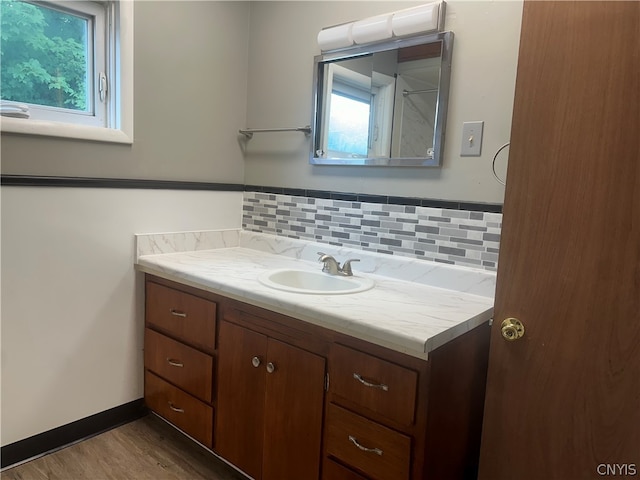 bathroom featuring a healthy amount of sunlight, hardwood / wood-style floors, tasteful backsplash, and vanity