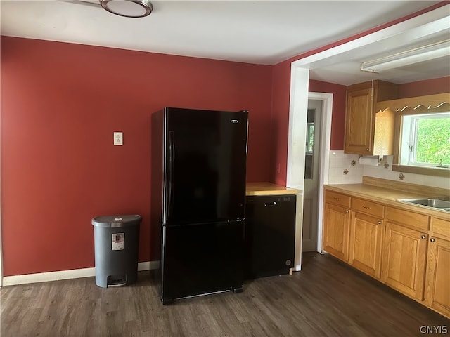 kitchen featuring black fridge, sink, dark hardwood / wood-style flooring, and tasteful backsplash