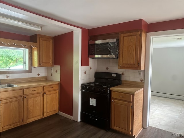 kitchen featuring backsplash, black range with gas stovetop, sink, and dark tile floors