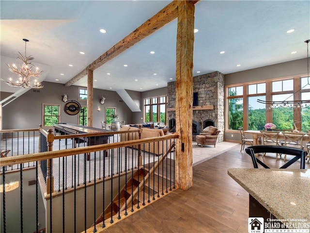 interior space with hardwood / wood-style floors, a fireplace, beamed ceiling, plenty of natural light, and a chandelier