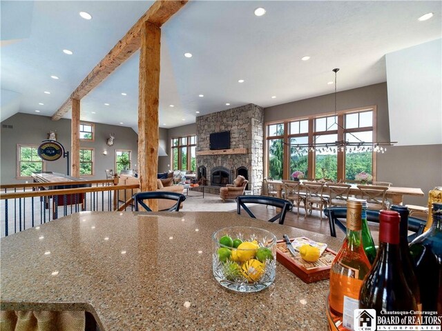 kitchen with beam ceiling, stone counters, a fireplace, and pendant lighting