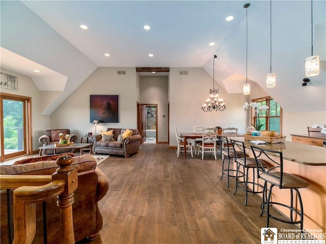 living room with dark hardwood / wood-style flooring, lofted ceiling, and an inviting chandelier