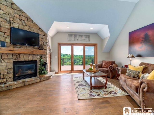 living room with a stone fireplace, vaulted ceiling, and hardwood / wood-style flooring