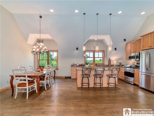 kitchen with dark wood-type flooring, stainless steel appliances, a notable chandelier, pendant lighting, and a breakfast bar