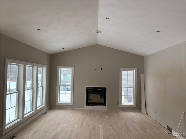 unfurnished living room featuring a healthy amount of sunlight, light hardwood / wood-style flooring, and vaulted ceiling