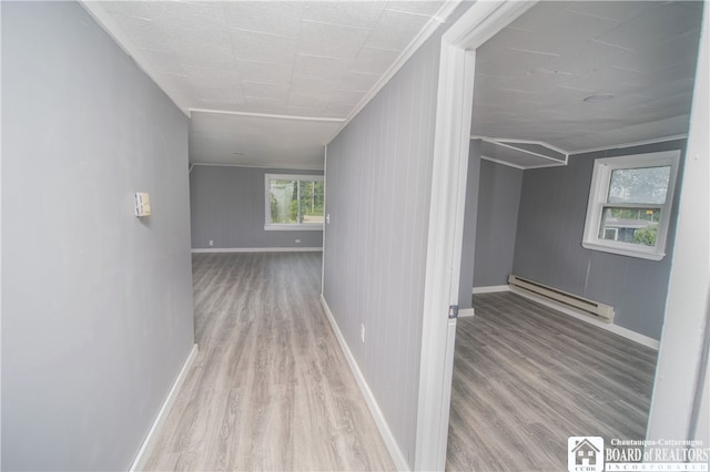 hall with a baseboard heating unit, ornamental molding, and light hardwood / wood-style floors