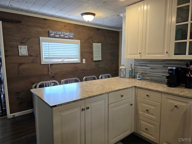 kitchen featuring white cabinetry, wooden walls, dark hardwood / wood-style flooring, and light stone countertops